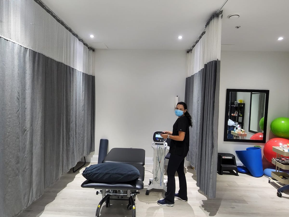A therapist setting up the electrotherapy unit in a treatment bay at the clinic